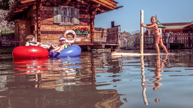 Kinder spielen am Naturbadeteich mit Schwimmreifen